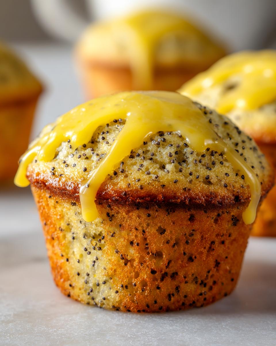 A close-up of a moist lemon poppy seed muffin topped with bright yellow lemon glaze dripping down the sides.