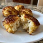 A perfectly cooked Maryland crab cake broken open to show the flaky white crab meat inside.