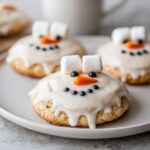 Close-up of delicious melted snowman cookies decorated with white icing, marshmallow hats, and candy features.