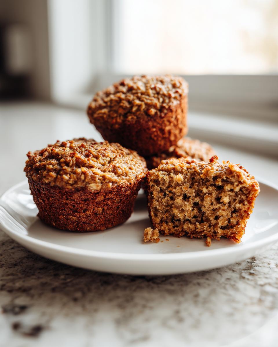 Close-up of moist banana oatmeal muffins, one cut in half showing the texture.