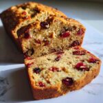 Close-up of moist cranberry walnut bread, showing bright red cranberries and chopped walnuts in the crumb.