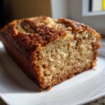 Close-up of a moist slice of greek yogurt banana bread featuring a crunchy, sugary cinnamon topping.