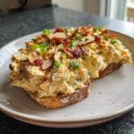 A generous serving of creamy Neiman Marcus dip piled high on toasted bread, topped with sliced almonds and bacon.