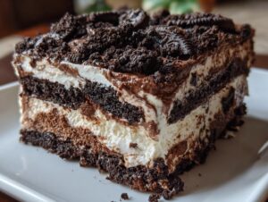 Close-up of a layered slice of rich Oreo dirt cake showing chocolate crumbs and creamy filling.