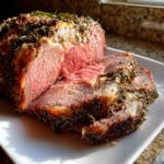 A perfectly cooked prime rib roast oven preparation, sliced to show medium-rare center and herb crust.