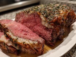 Close-up of a perfectly cooked prime rib roast oven preparation, sliced to show medium-rare center and herb crust.