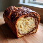 A freshly baked loaf of pumpkin sourdough bread, sliced to show the interior swirl filling.