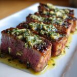 Four thick slices of perfectly seared tuna steak, medium-rare inside, topped with melting herb garlic butter.