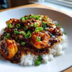 A close-up of flavorful shrimp étouffée served over a bed of fluffy white rice and garnished with fresh green onions.