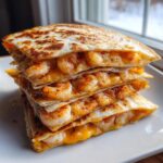 A tall stack of golden-brown shrimp quesadilla quarters filled with seasoned shrimp and melted cheese.