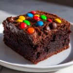A rich, fudgy square of cosmic brownies topped with chocolate frosting and colorful candy-coated chocolates.
