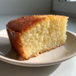 Close-up of a moist slice of yellow condensed milk cake with a golden brown, slightly sticky top.