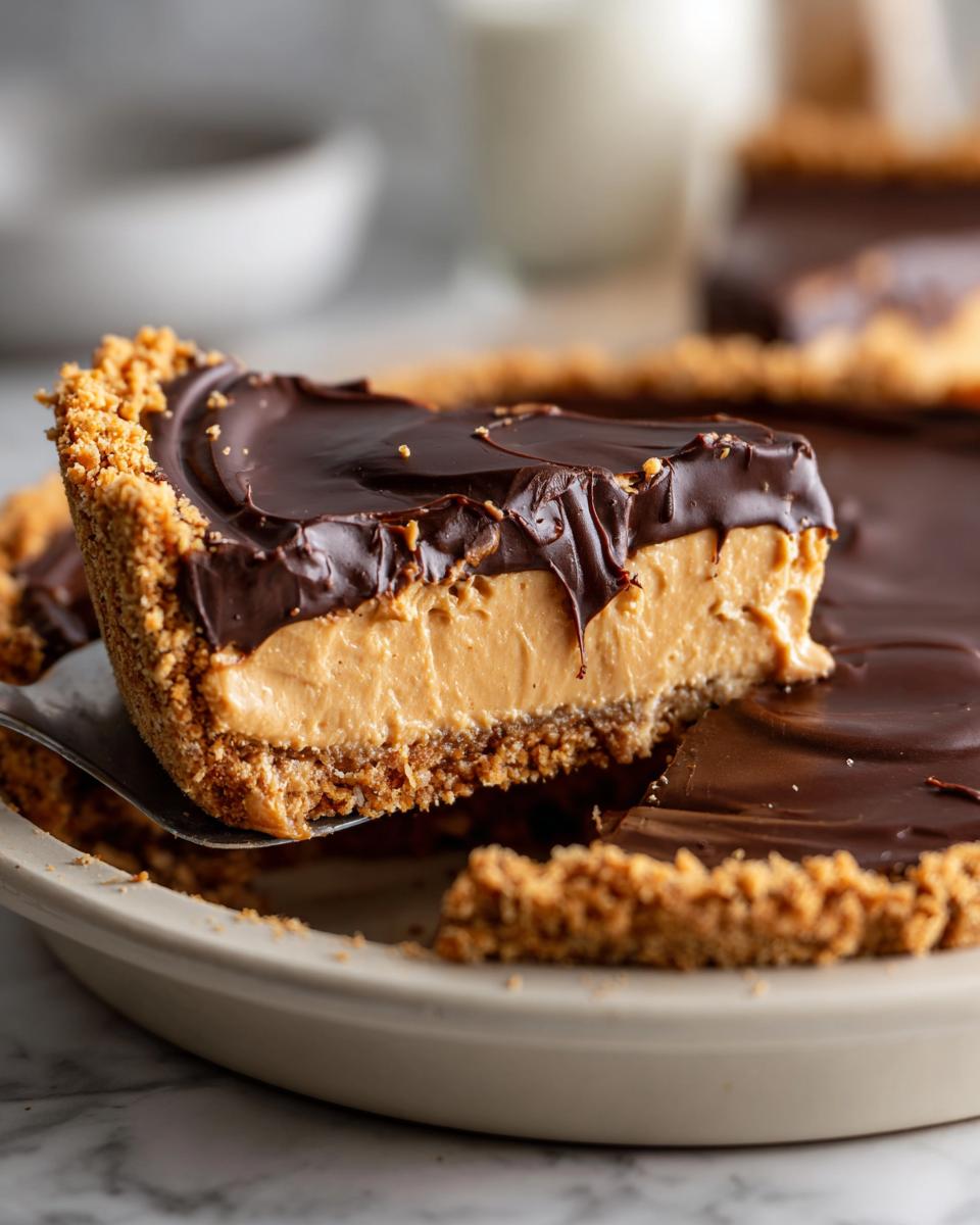 A slice being lifted from a creamy peanut butter pie featuring a graham cracker crust and thick chocolate topping.