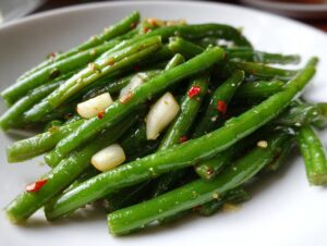 A close-up of bright green, glossy dilly beans seasoned with garlic cloves and red pepper flakes.