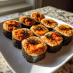 Eight slices of homemade tuna kimbap featuring spicy tuna filling and topped with shredded seaweed, ready to eat.