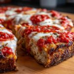 Close-up of a thick slice of chicken crust pizza showing the dense crust, melted mozzarella, and bright red sauce.
