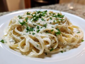 Close-up of fettuccine pasta coated in rich vegan alfredo sauce and topped with fresh parsley.