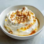 Close-up of creamy whipped goat cheese topped with chopped nuts and drizzled with golden honey.