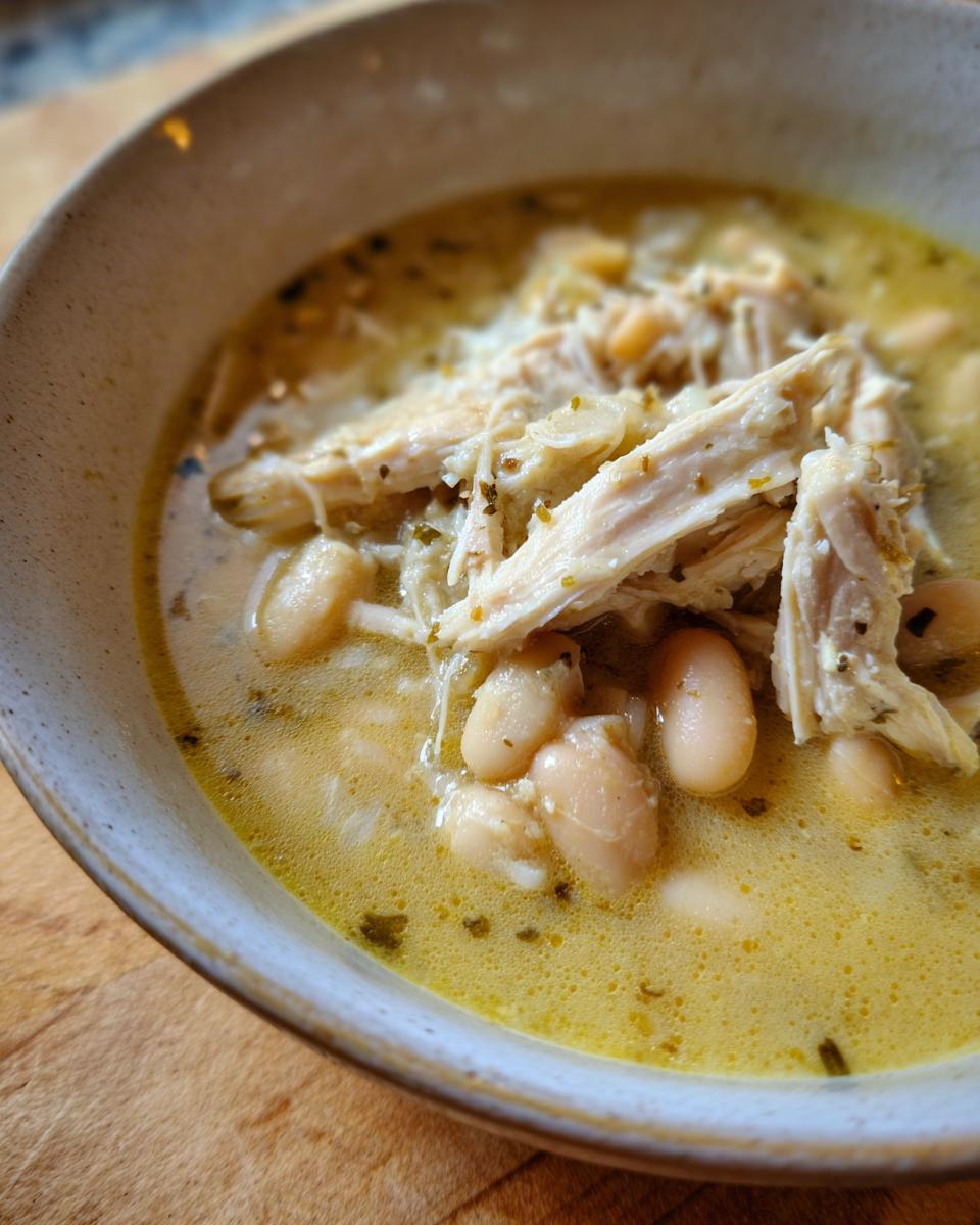 A close-up view of a hearty bowl of white chicken chili recipe, featuring shredded chicken and white beans in a creamy broth.