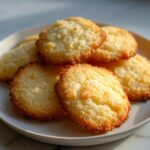 A close-up of several golden brown 3-ingredient butter cookies stacked on a white plate.