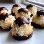 Several homemade almond joy truffles made with coconut, dipped in dark chocolate, and topped with a whole almond.