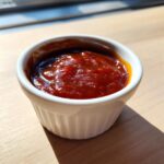 Close-up of rich, glossy homemade bbq sauce served in a small white fluted ramekin.