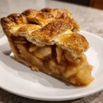Close-up of a thick slice of amazing apple pie showing a golden lattice crust and caramelized apple filling.