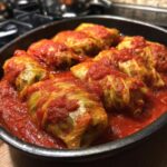 Close-up of several homemade cabbage rolls covered in rich tomato sauce, ready to serve.