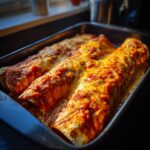 Close-up of bubbling, cheesy cheese enchiladas covered in red sauce, fresh from the oven.