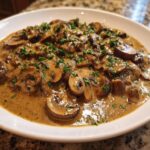 Close-up of a rich, creamy mushroom sauce loaded with sliced mushrooms and topped with fresh parsley.
