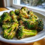 A close-up of perfectly roasted broccoli florets, seasoned and topped with grated cheese.
