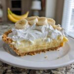 A generous slice of banana cream pie showing graham cracker crust, creamy filling, whipped cream, and banana slices.