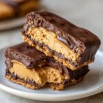 Two stacked bars of rich buckeye graham crackers showing a thick peanut butter filling and chocolate coating.