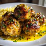 Close-up of browned chicken piccata meatballs covered in a bright lemon-butter sauce with capers and parsley.