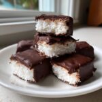Stack of chocolate-covered coconut bars, a type of cool whip candy, showing the fluffy white interior.