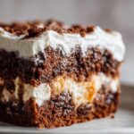 A close-up, cross-section view of a rich, dark gingerbread trifle slice showing layers of cake, cream, and crumbs.