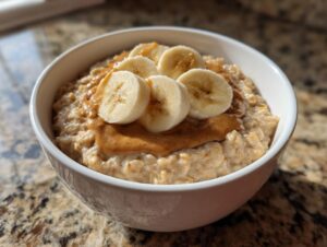A close-up of creamy banana oatmeal topped with a swirl of peanut butter and fresh banana slices.