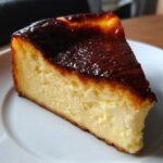 A close-up of a creamy slice of basque cheesecake featuring its signature dark, caramelized top.