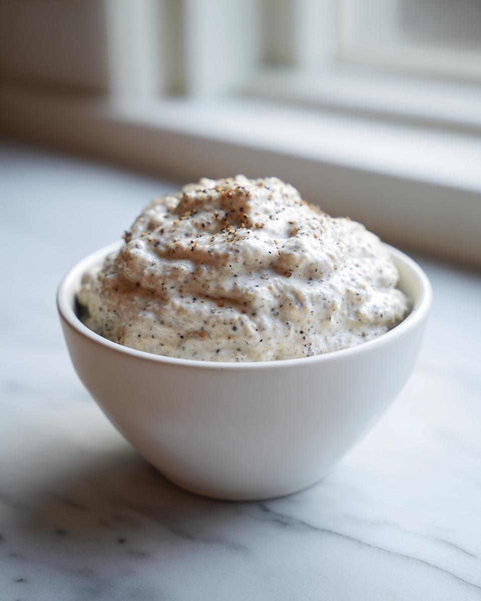 A close-up of thick, creamy chia seed pudding topped with a sprinkle of seeds in a white bowl.