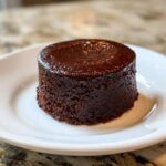 A perfectly molded, dark brown individual serving of creamy chocolate pudding with a glossy top.