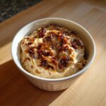 A white ramekin filled with creamy onion dip, generously topped with crispy caramelized onions.