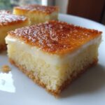 A square slice of moist cassava cake with a creamy white layer and a caramelized, golden-brown top.