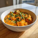 A close-up of a creamy vegan pumpkin curry served in a white bowl, garnished generously with fresh cilantro.