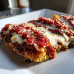 Close-up of a crispy keto chicken parmesan serving topped with melted mozzarella and marinara sauce.