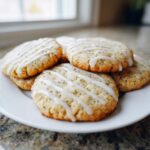A stack of freshly baked Earl Grey cookies topped with a white lemon glaze drizzle on a white plate.