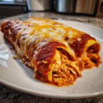 Two rolled easy chicken enchiladas smothered in red sauce and topped with melted cheddar and Monterey Jack cheese.