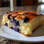Close-up of a fluffy slice of blueberry sheet pan pancakes with a golden-brown top.