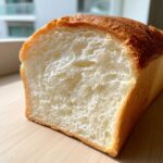 Close-up of the soft, white crumb texture inside a freshly baked loaf of condensed milk bread.