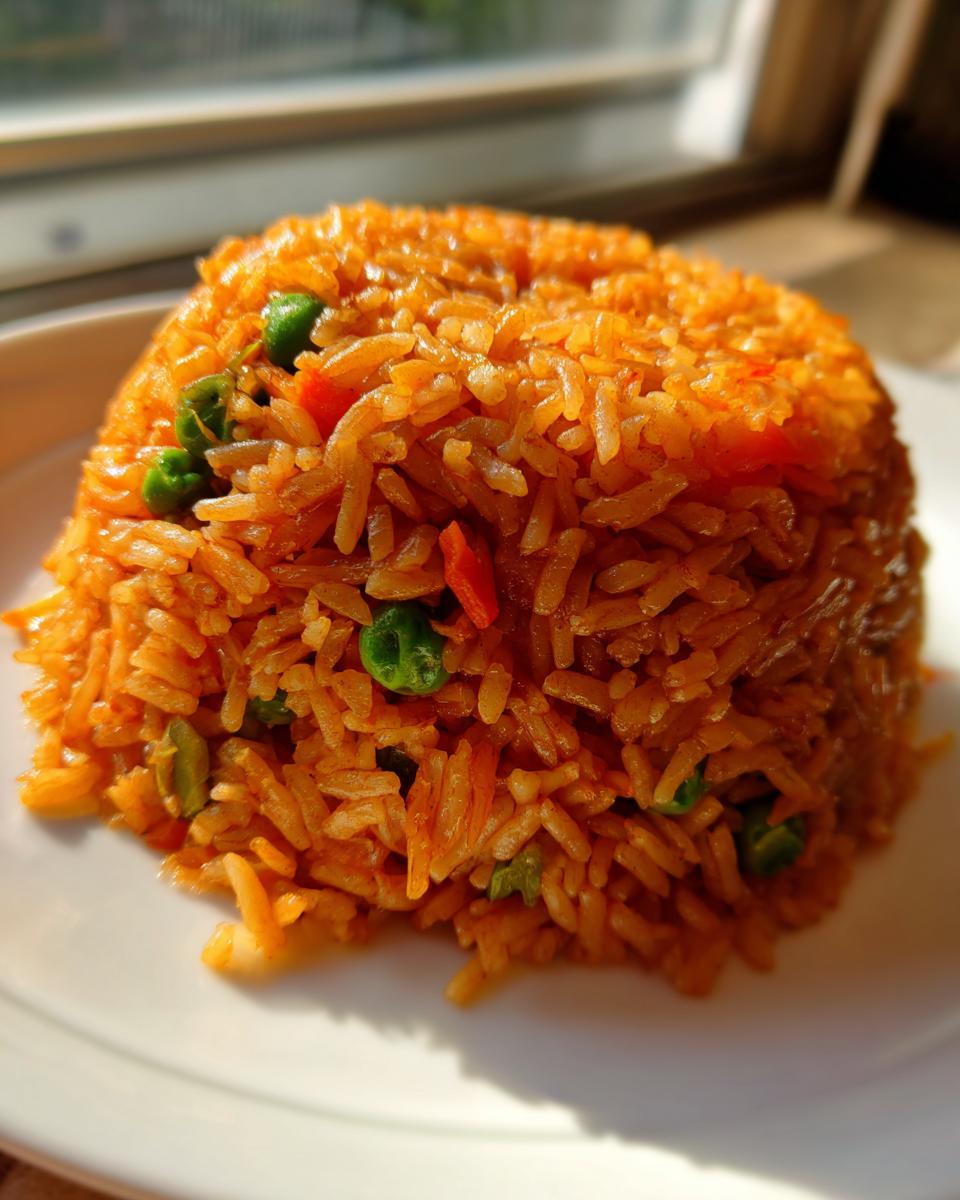 A perfectly molded mound of fluffy, orange-colored mexican rice mixed with bright green peas and diced carrots.