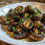 A close-up of glossy, sautéed garlic butter mushrooms topped with fresh chopped parsley.